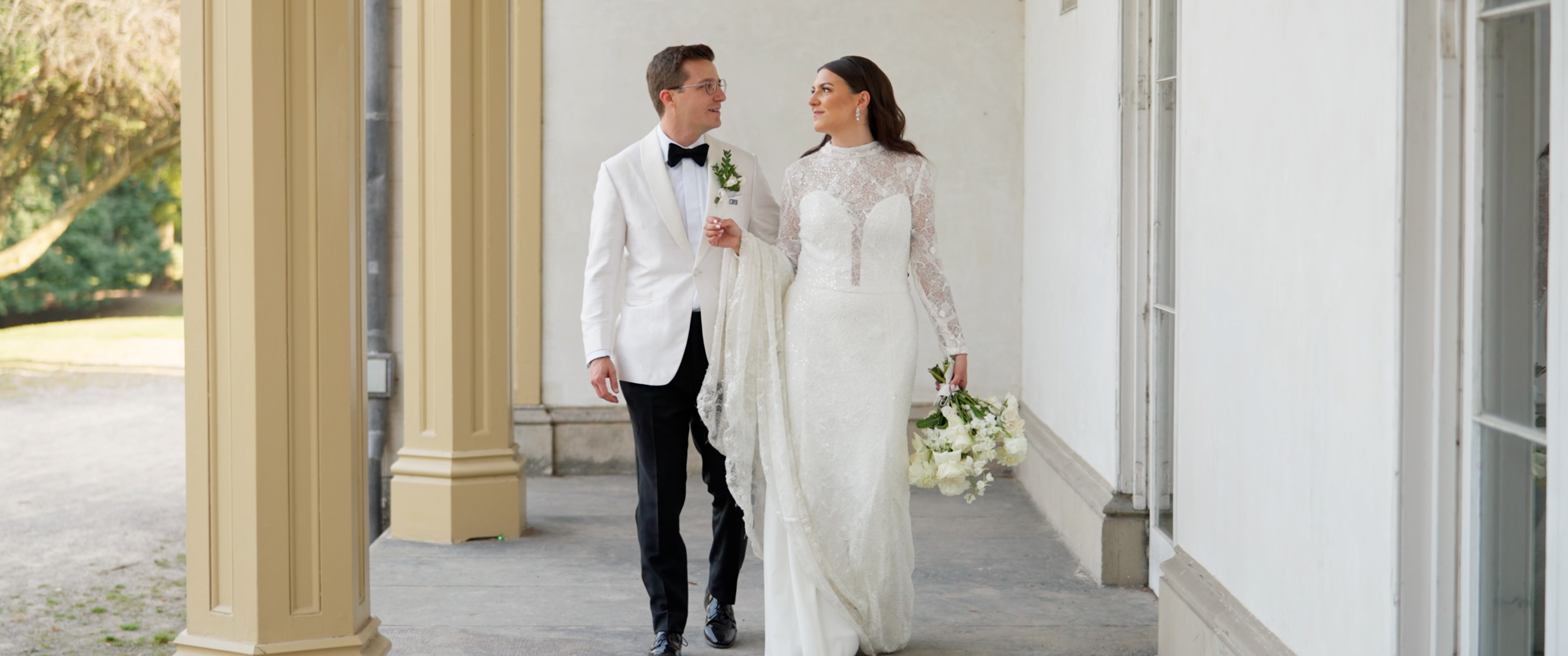 Couple walking through colonnade on wedding day